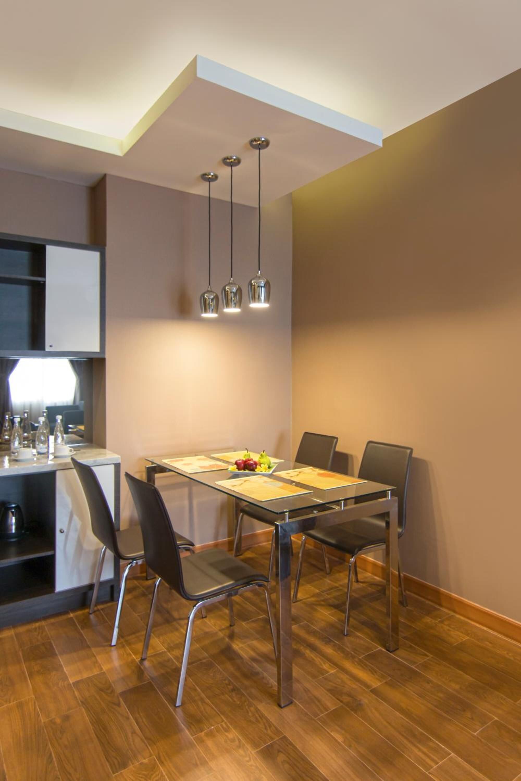 A modern dining area with a wooden table, four chairs, and pendant lighting.