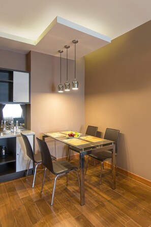 Un espace de salle à manger moderne avec une table en bois, quatre chaises et des luminaires suspendus.