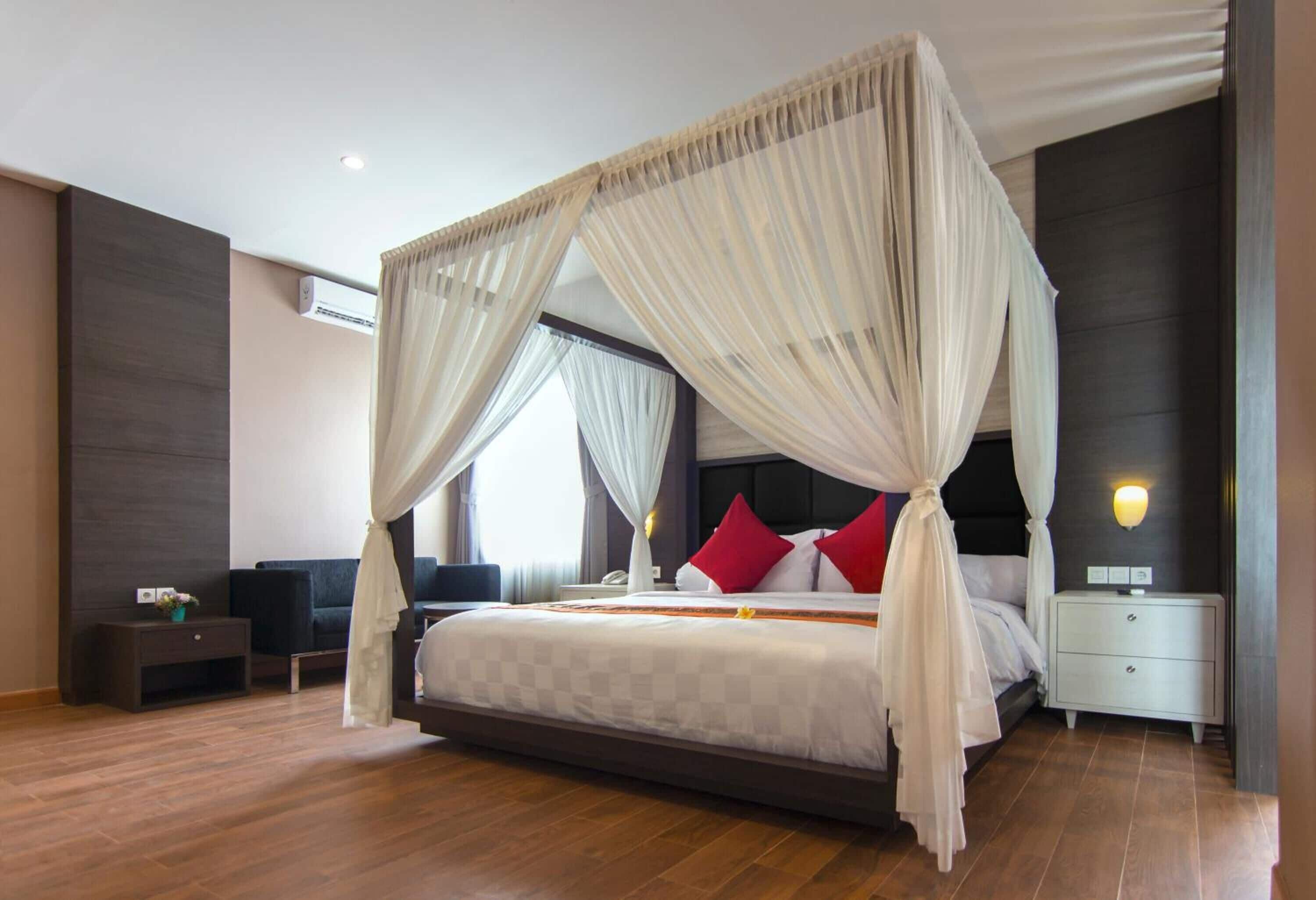 A spacious bedroom with a large bed, a bedside table, a nightstand, and a wall-mounted air conditioning unit.