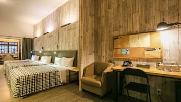 A hotel room with a wooden wall, a bed with checkered bedding, a desk with a lamp, and a chair.
