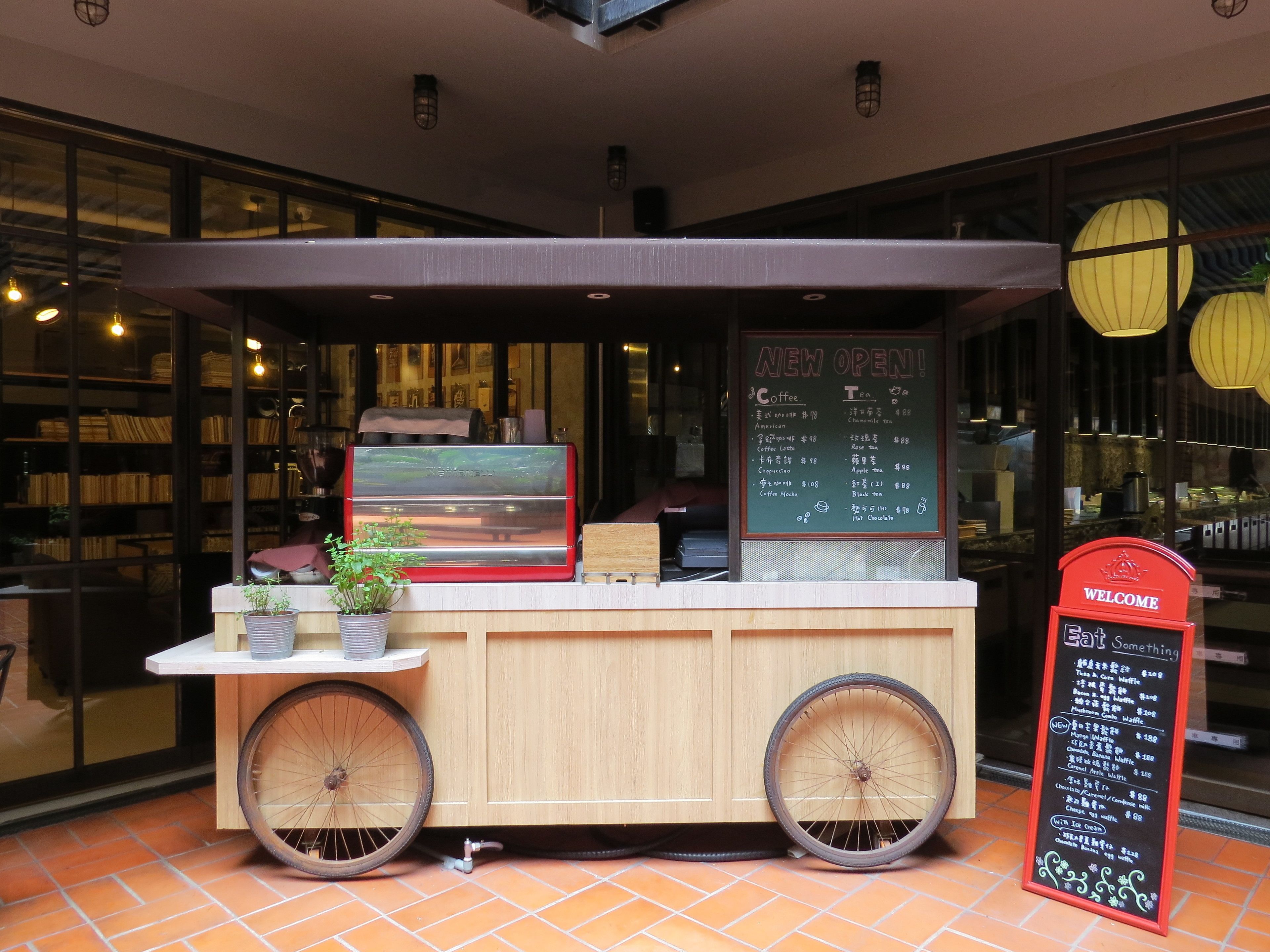 A coffee cart with a menu board and a welcome sign.