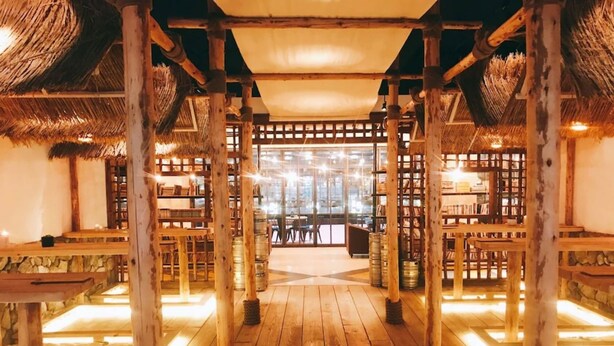 A wooden floor with tables and chairs under a thatched roof structure. - Hotel Papa Whale (Taipei)