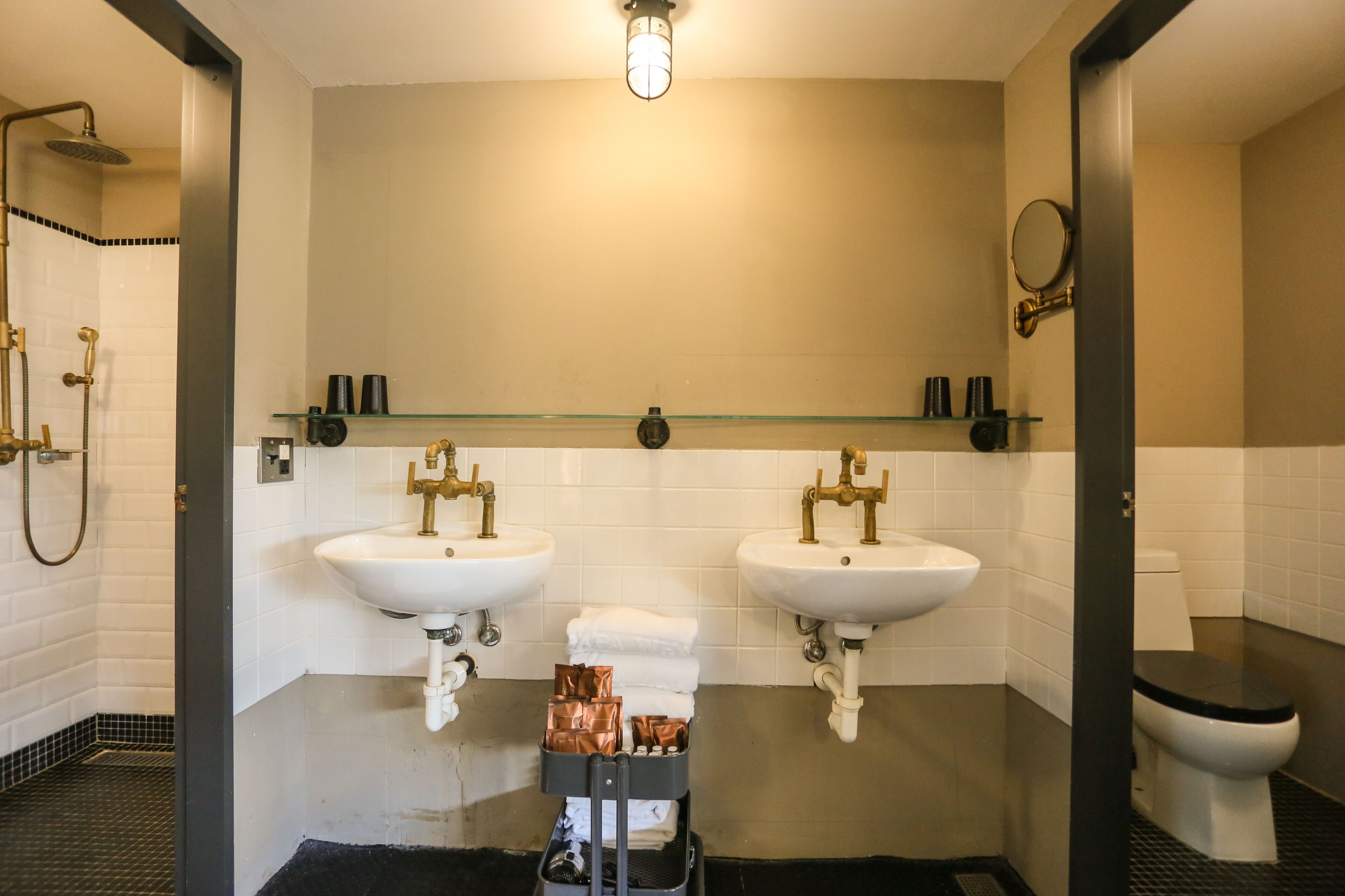 A modern bathroom with two sinks, a toilet, and a shower.