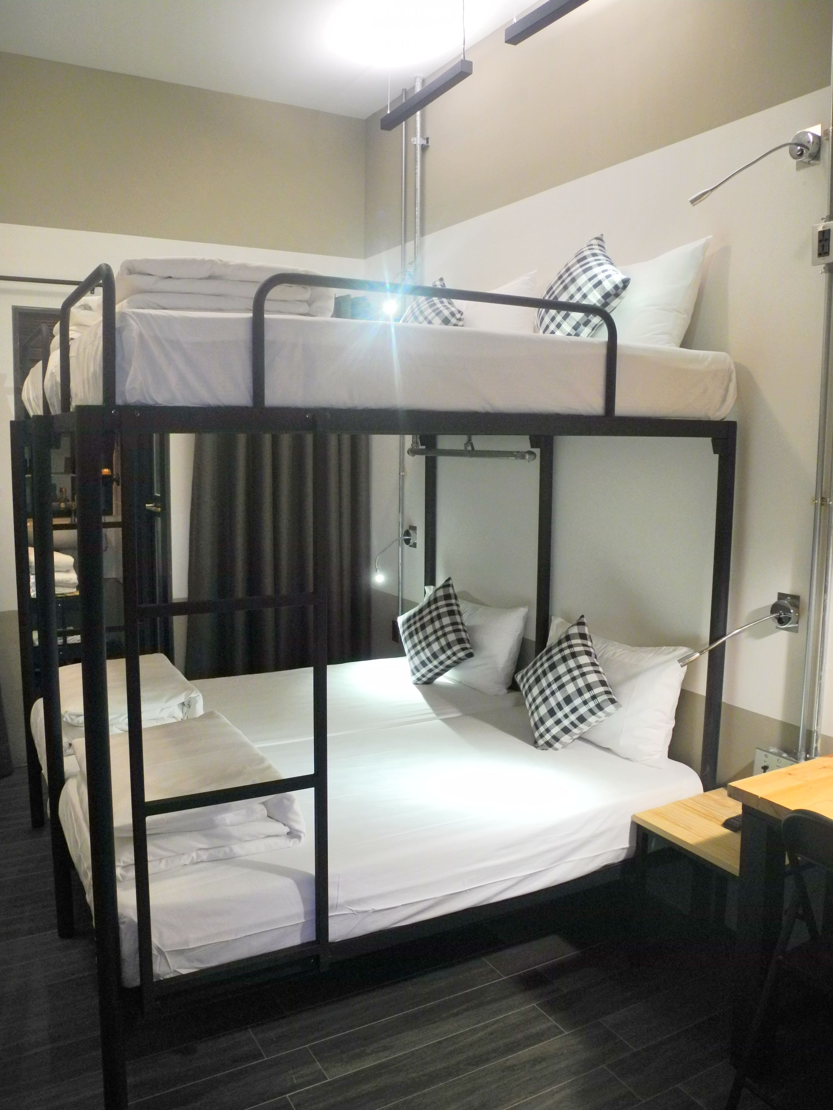 A bunk bed room with white bedding and checkered pillows.