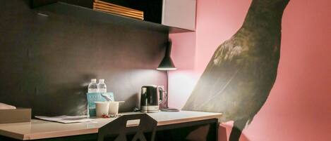 A small, modern room with a desk, chair, and a large wall mural of a bird.