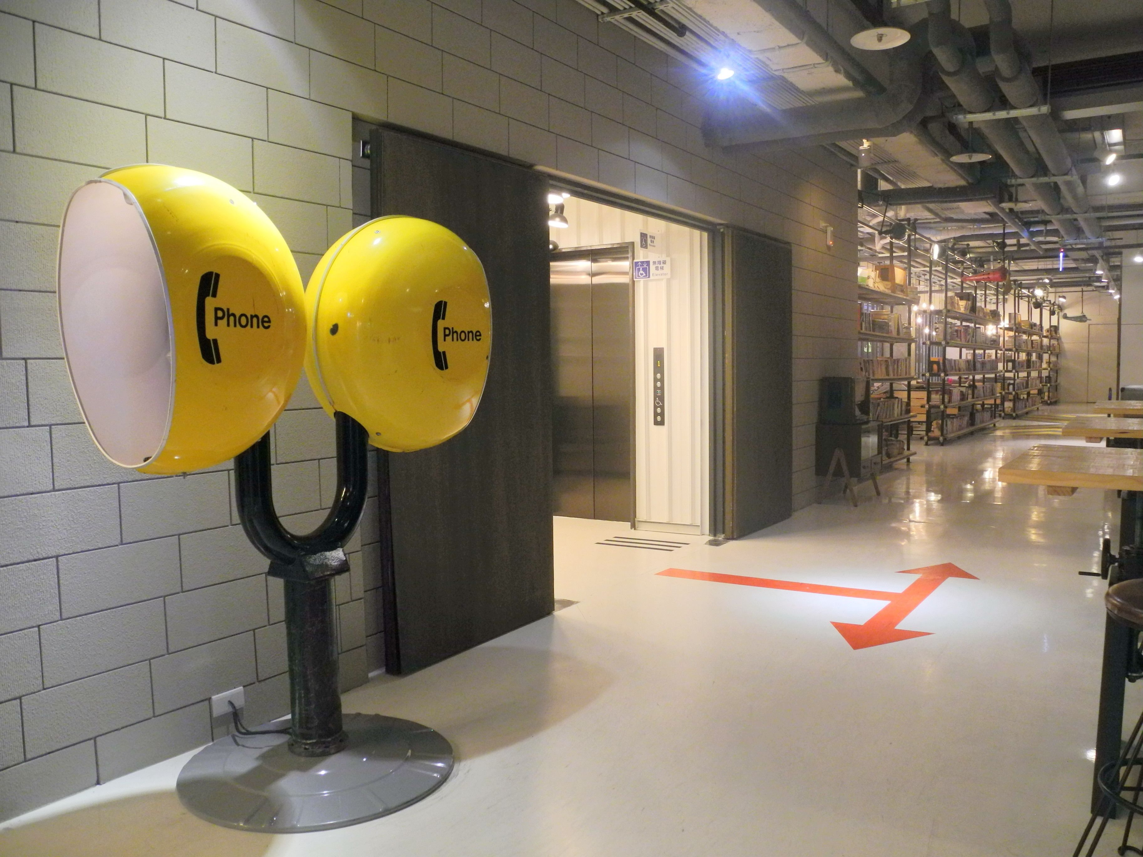 A hallway with a directional sign and a door with a sign indicating a phone.