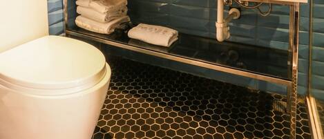 Un baño con inodoro blanco, un lavabo con espejo y suelo de baldosas.