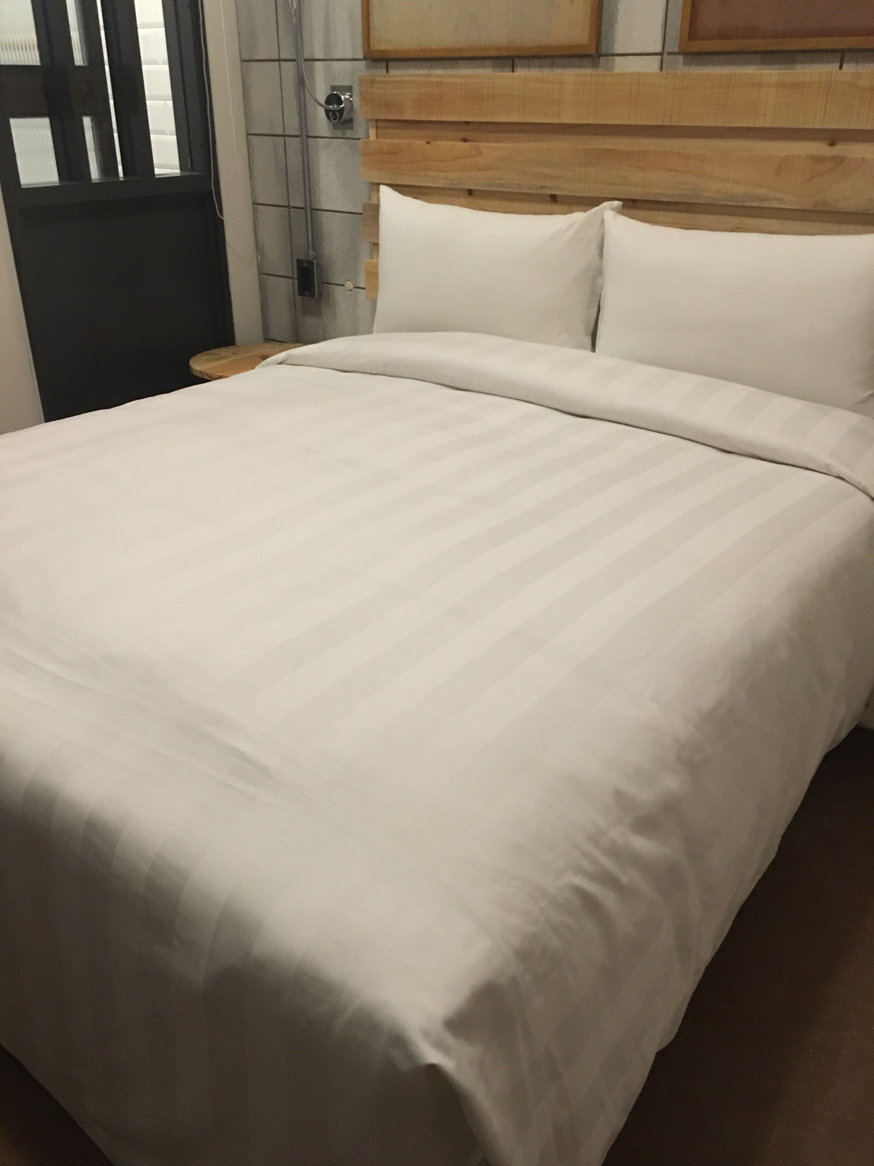 A neatly made bed with white linens in a hotel room.