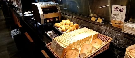 A buffet area with various food items, including bread and rolls, and a sign with Chinese characters.