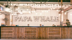 A reception desk with a sign reading "PAPA WHALE" and a wooden slatted design. - Hotel Papa Whale (Taipei)