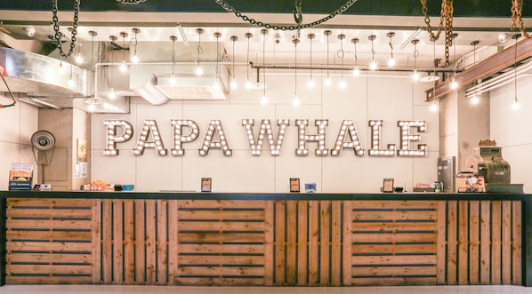 A reception desk with a sign reading "PAPA WHALE" and a wooden slatted design.