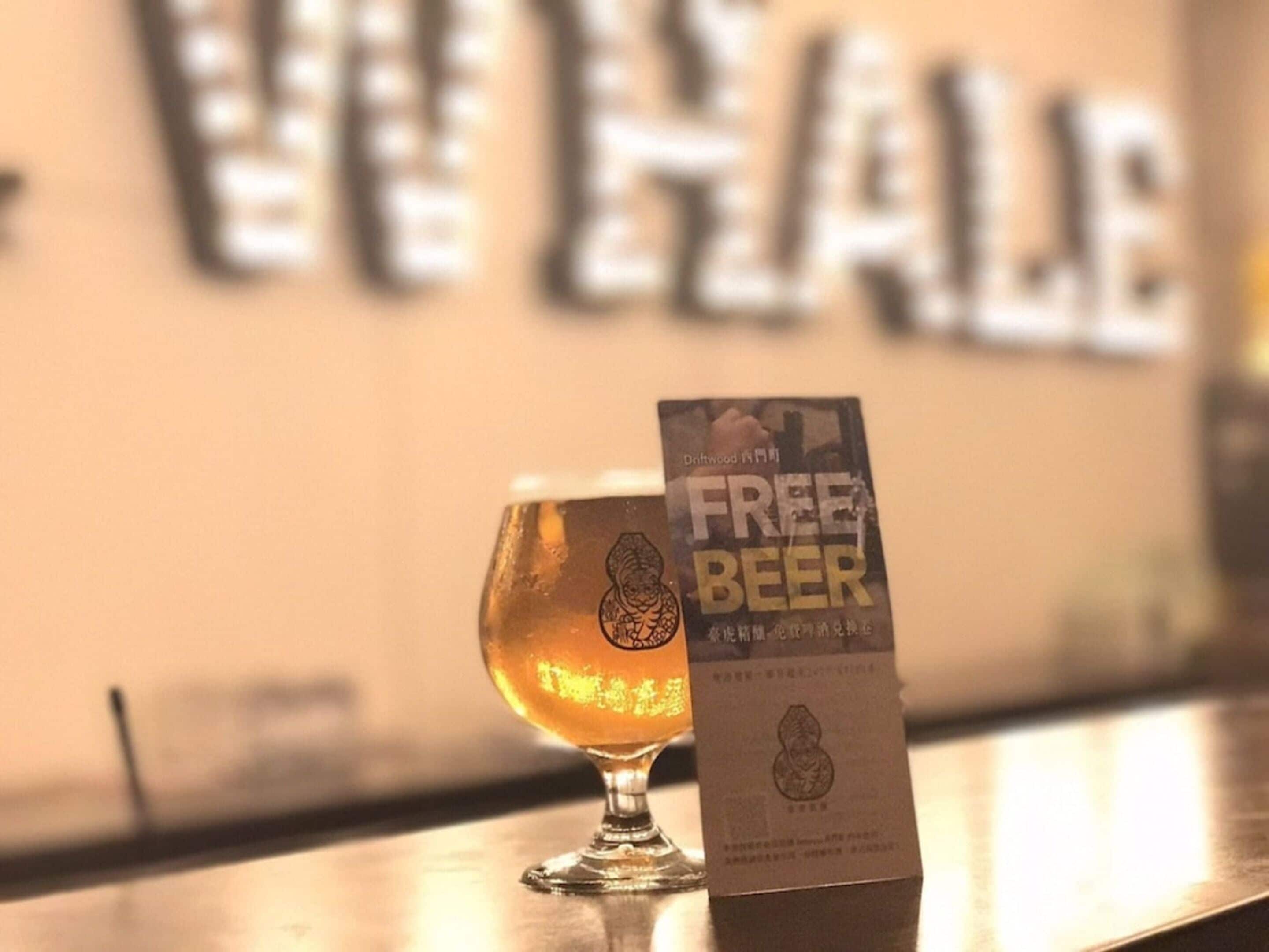 Um copo de cerveja em um balcão de bar com um aviso de cerveja grátis.