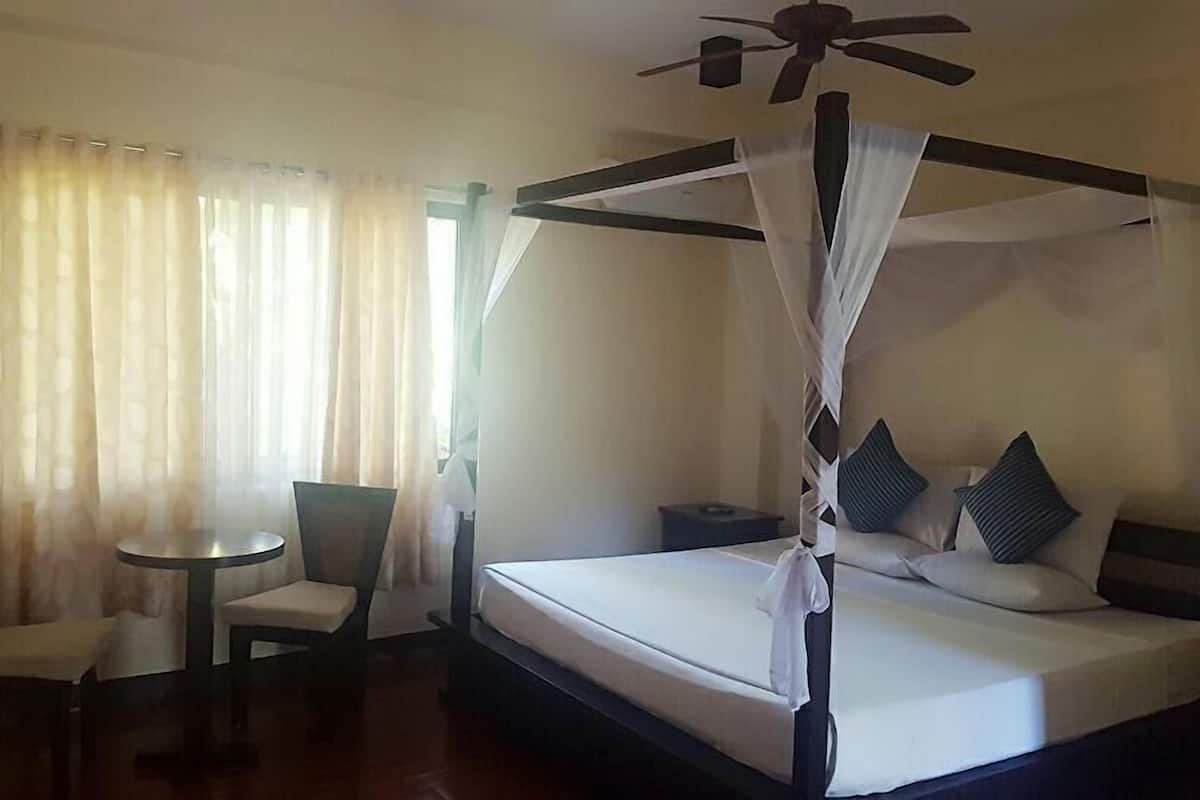 Un lit à baldaquin, une table ronde et deux chaises dans une chambre d’hôtel.