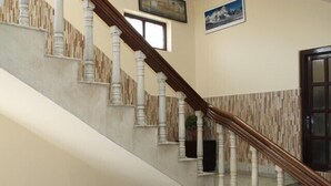 A staircase with white balusters and a wooden handrail, leading to a landing with a door and a window. - Thamel Apartments Hotel (Kathmandu)