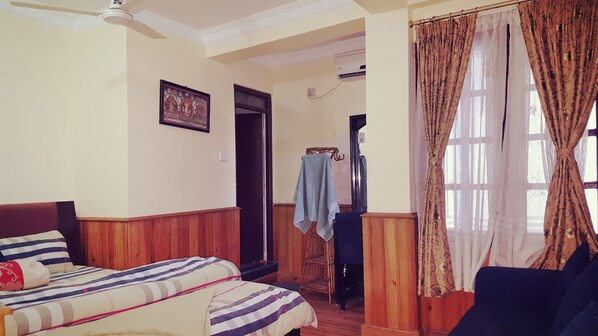 A bedroom with a bed, a chair, a wardrobe, and a door leading to another room.
