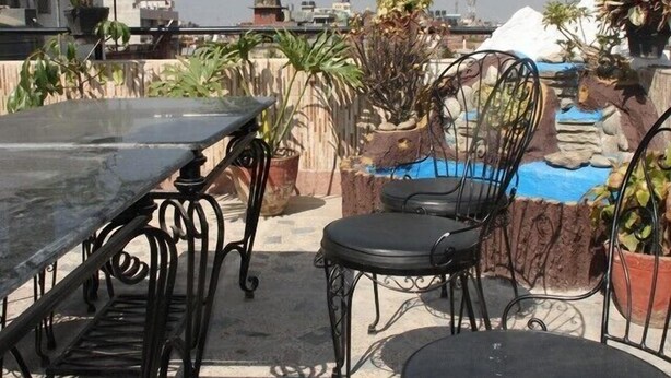 A rooftop terrace with a table and chairs, potted plants, and a small water feature. - Thamel Apartments Hotel (Kathmandu)