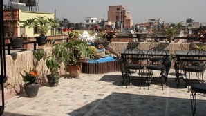 A rooftop terrace with potted plants, outdoor seating, and a view of surrounding buildings. - Thamel Apartments Hotel (Kathmandu)