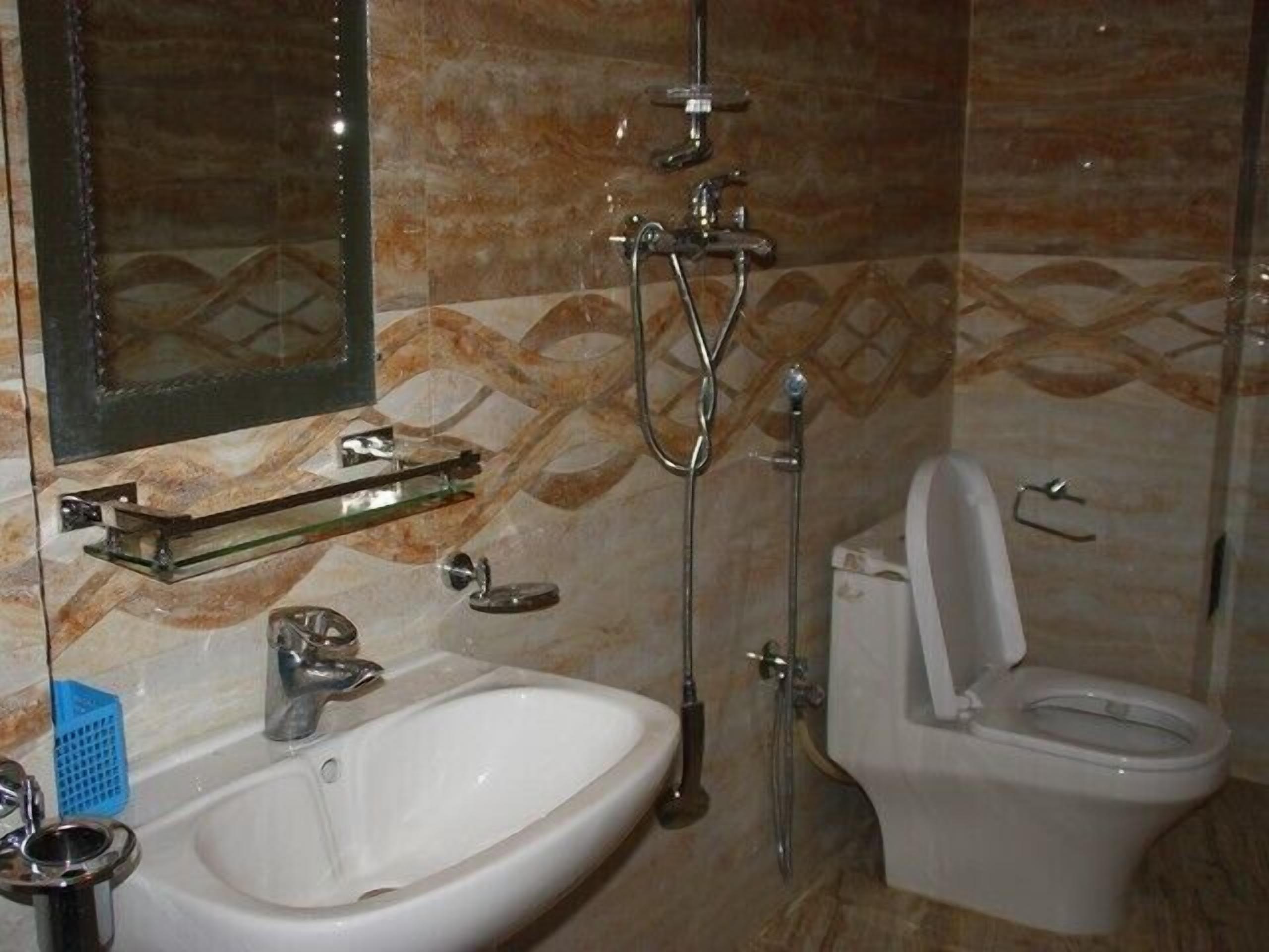 A bathroom with a sink, mirror, shower, and toilet.