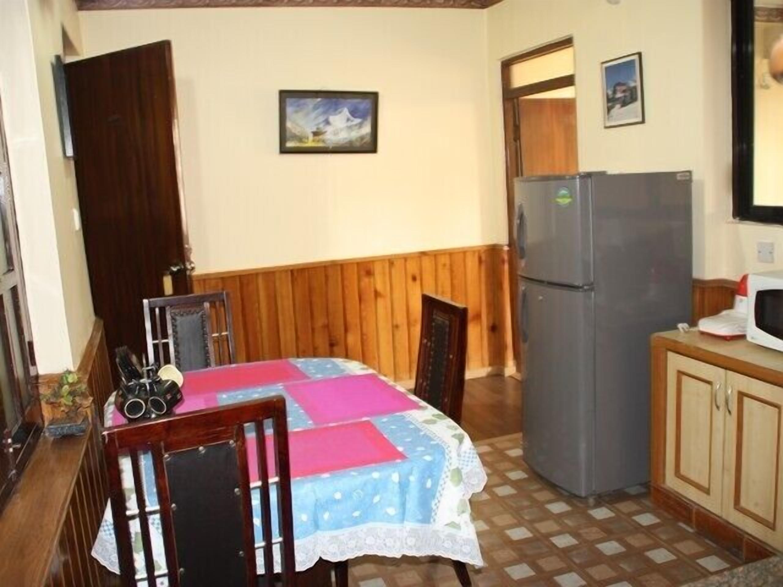 A compact kitchen with a refrigerator, microwave, and wooden cabinets.