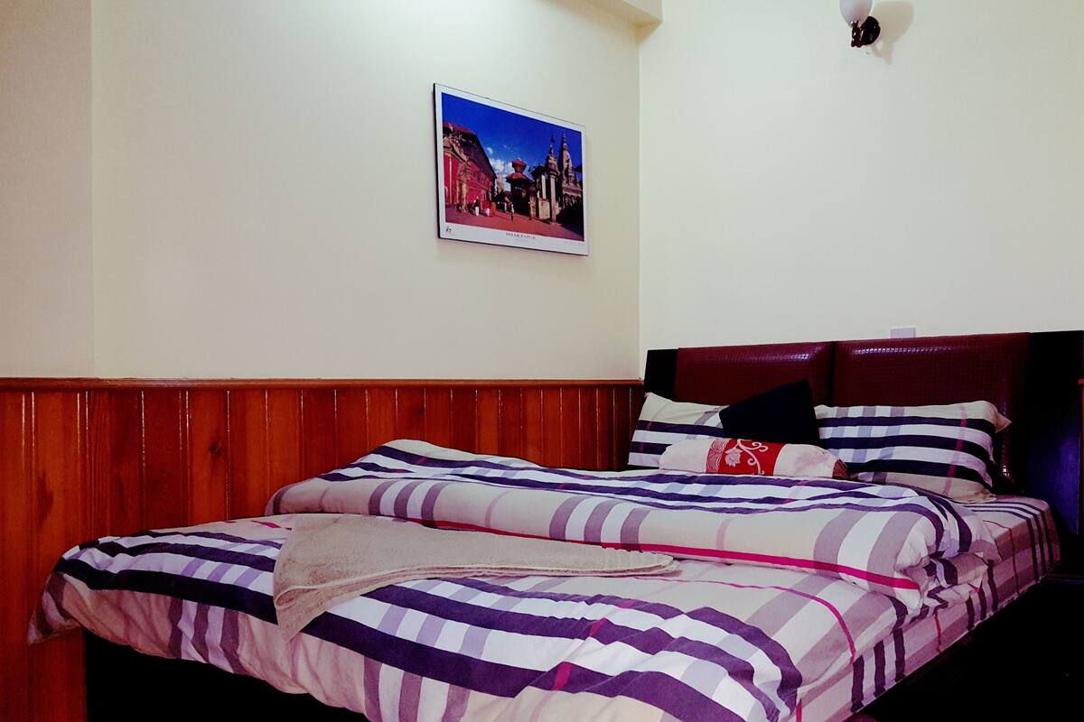 Una camera da letto con una testiera in legno, un letto con biancheria a righe e un quadro appeso al muro.