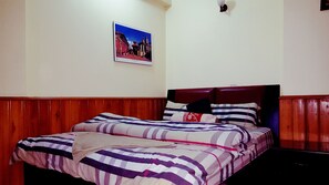 A bedroom with a wooden headboard, a bed with striped bedding, and a framed picture on the wall.