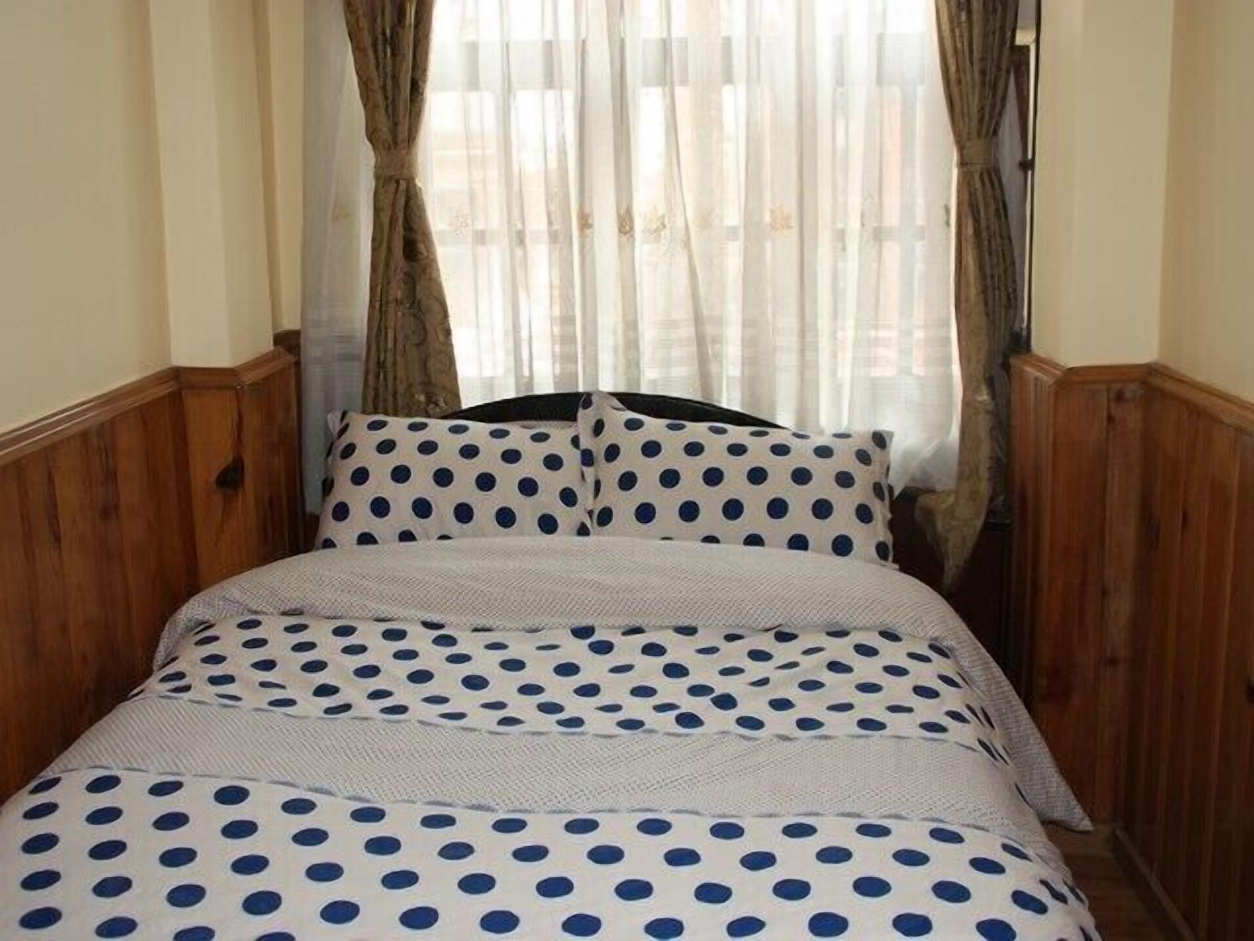 Una cama con ropa de cama de lunares y paneles de madera en las paredes.