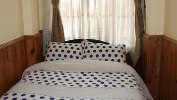 Una cama con ropa de cama de lunares y paneles de madera en las paredes.