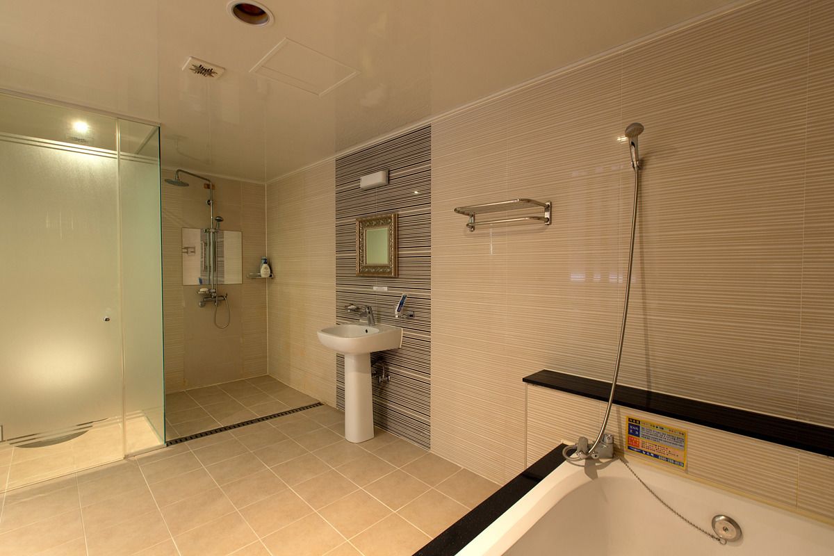 Un baño moderno con cabina de ducha de vidrio, lavamanos pedestal y bañera con detalle negro.