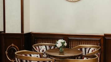 A dining area with a round table and four chairs, a wall clock, and a door with a no-smoking sign.