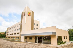 A modern building with a prominent tower featuring logos, a flat roof, and a large entrance with glass doors. - Slim Bento Goncalves (Bento Gonçalves)