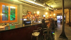 Una zona de bar con mostrador, taburetes y vistas a la calle.