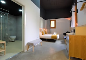 A compact hotel room with a bed, bedside table, bench, and a small desk. - Brick Palma (Palma de Mallorca)