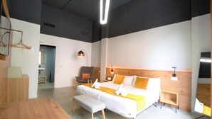 Una habitación de hotel moderna con una cama grande, un escritorio, una silla y una mesita de noche.