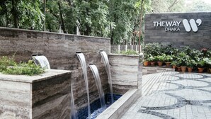 A water feature with multiple streams, a stone wall, and a sign for "The Way Dhaka". - THE WAY Dhaka (Dhaka)