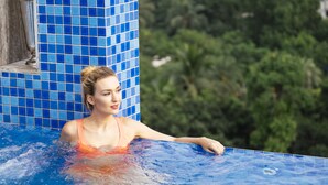 A person in a swimming pool with blue tiles and greenery in the background. - THE WAY Dhaka (Dhaka)