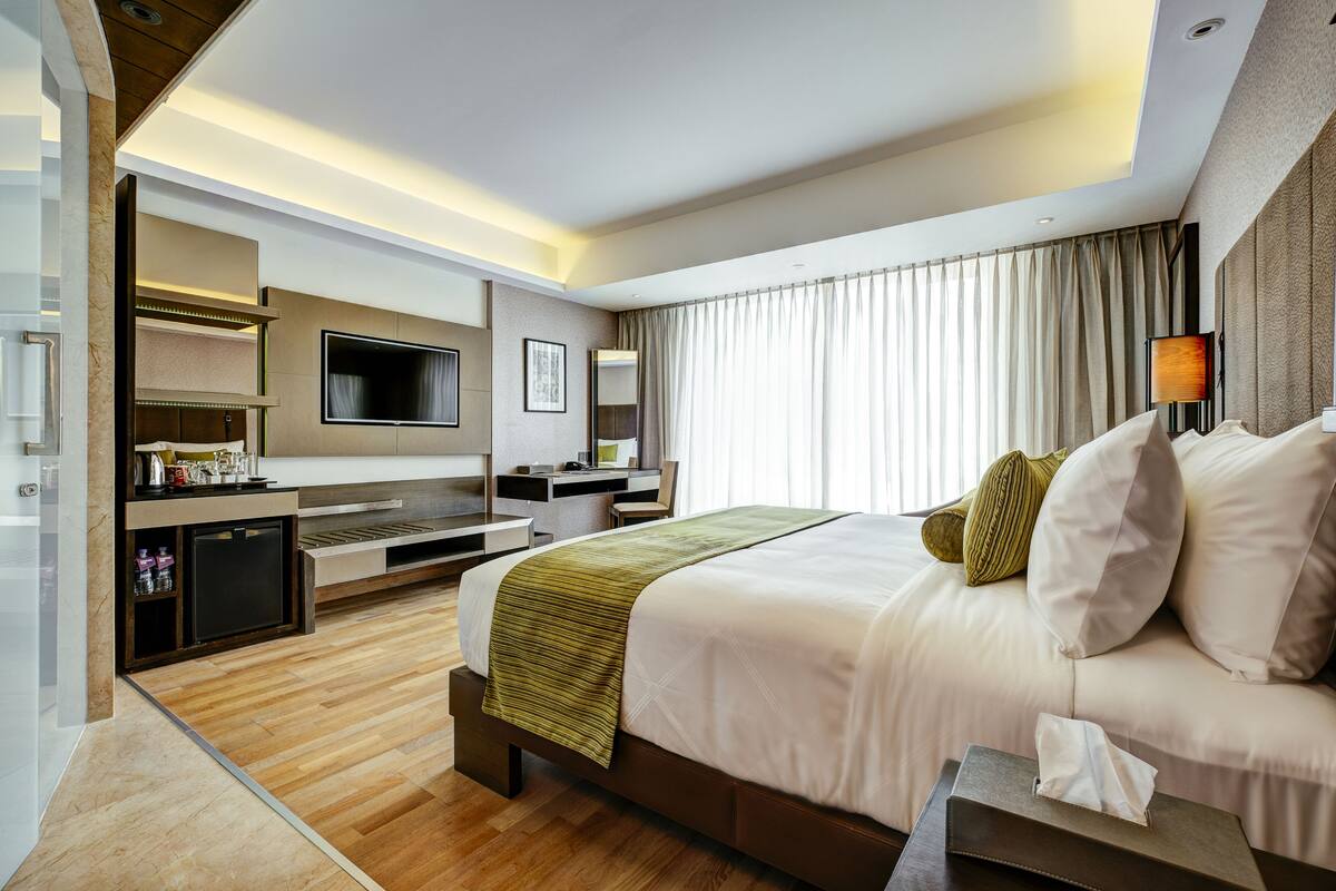 Una habitación de hotel moderna con una cama grande, un escritorio, un televisor y un minibar.
