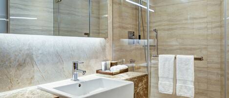 Un baño moderno con lavamanos de mármol, cabina de ducha de vidrio y un espejo grande.
