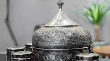 A decorative metal container with intricate designs, accompanied by smaller containers and a lamp in a modern setting.
