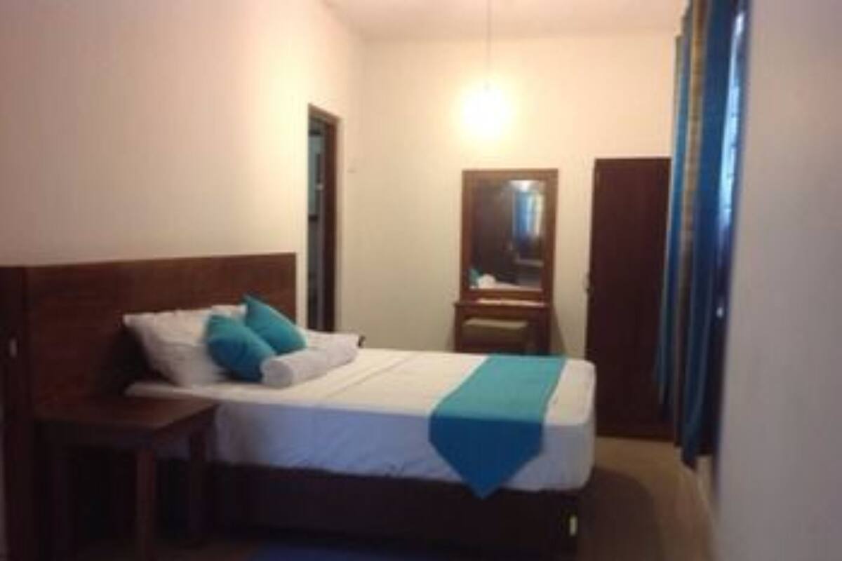 A bedroom with a bed, a nightstand, a mirror, and a door.