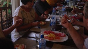 Un grupo de personas cenando en una mesa al aire libre, con botellas de agua y platos de comida.