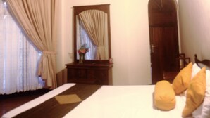 Un dormitorio con cama, espejo, puerta de madera y ventana con cortinas.