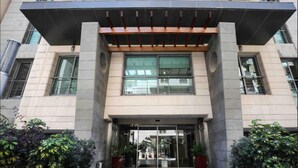 A modern building entrance with a covered walkway, large windows, and potted plants. - Sky Suites (Beirut)