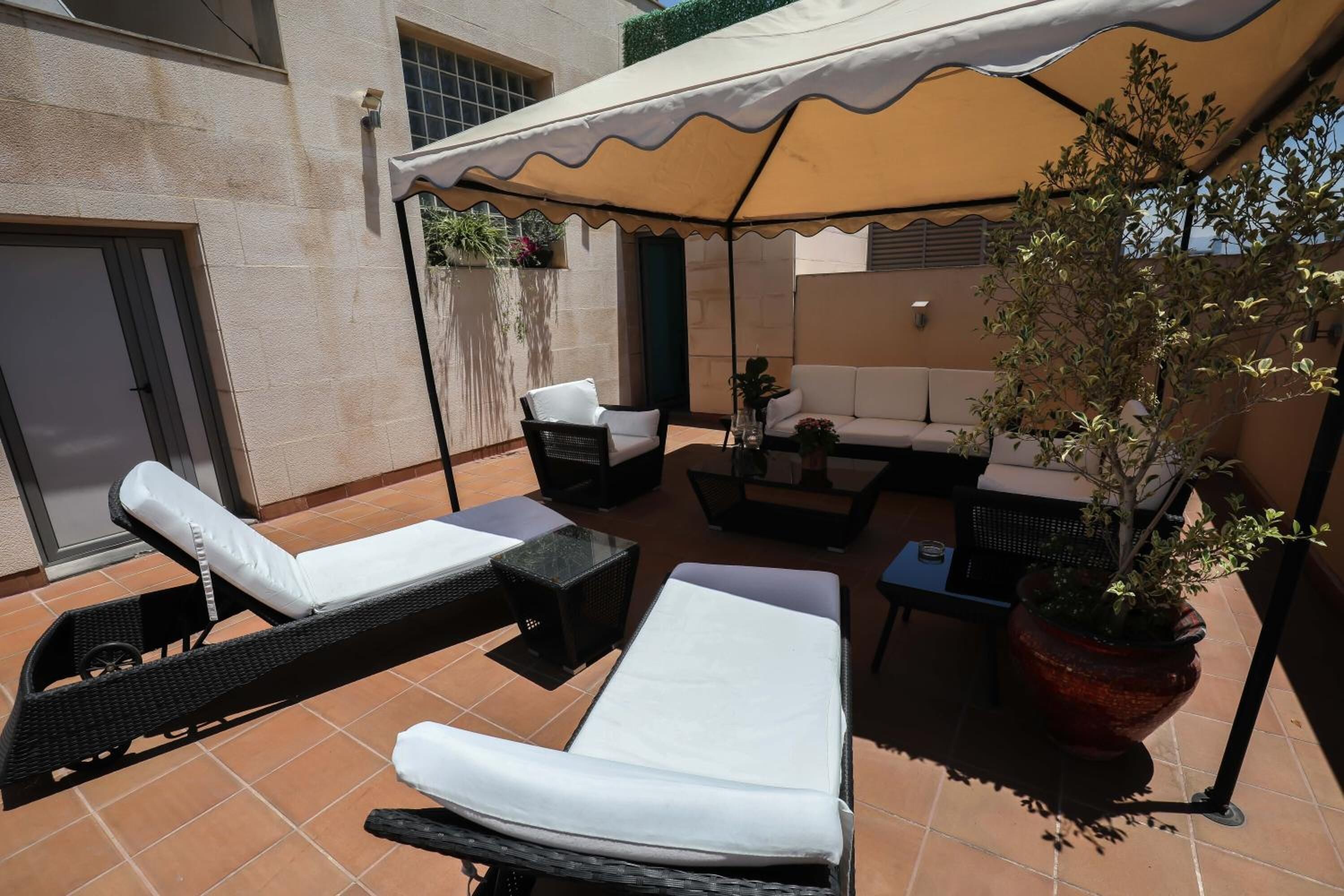 A patio with two lounge chairs, a sofa, and a table under a canopy.