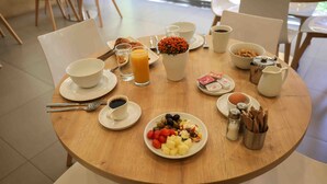 A breakfast table set with plates of fruit, cereal, coffee, and juice. - Sky Suites (Beirut)