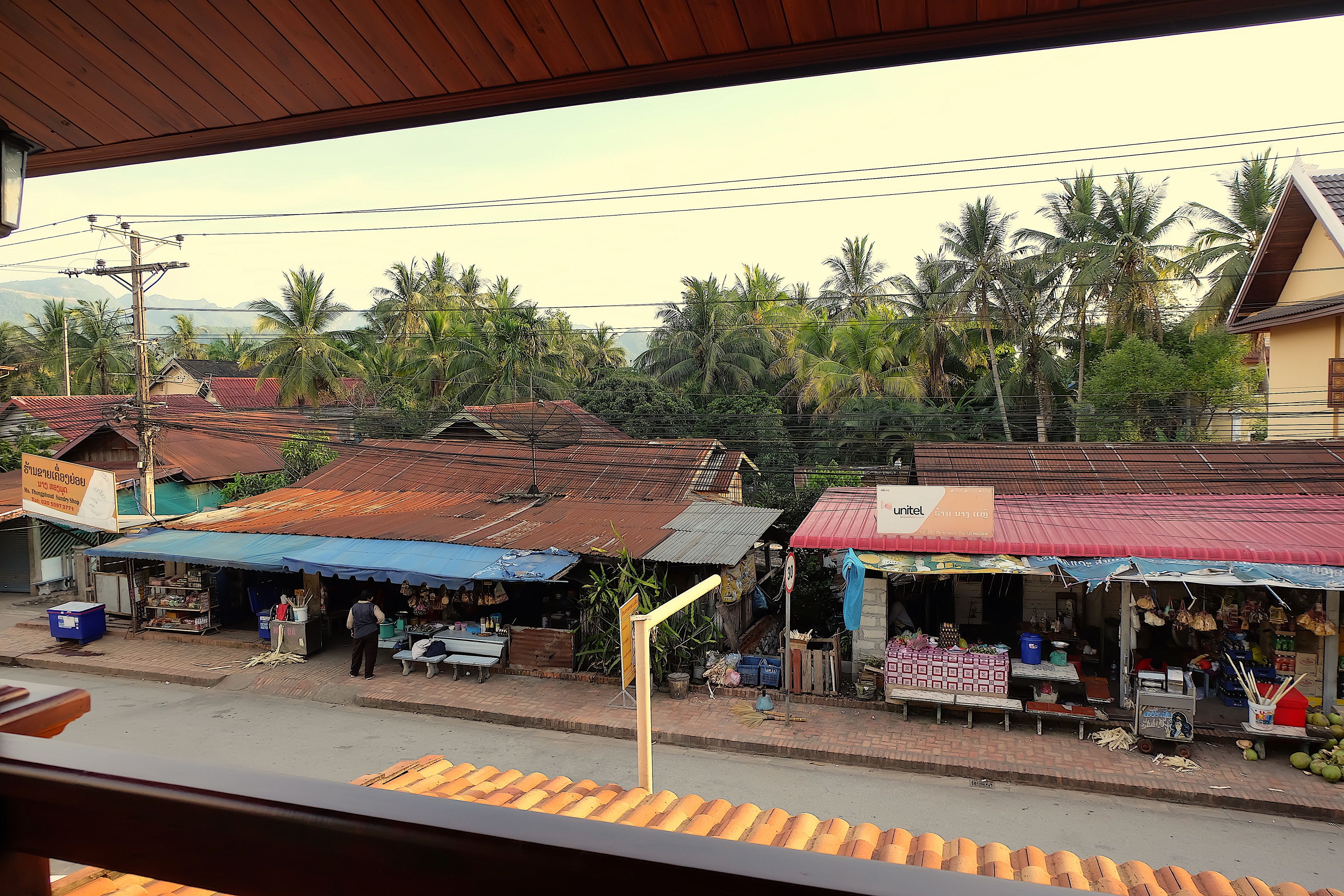 A street view with small shops, a blue umbrella, and a red roof.