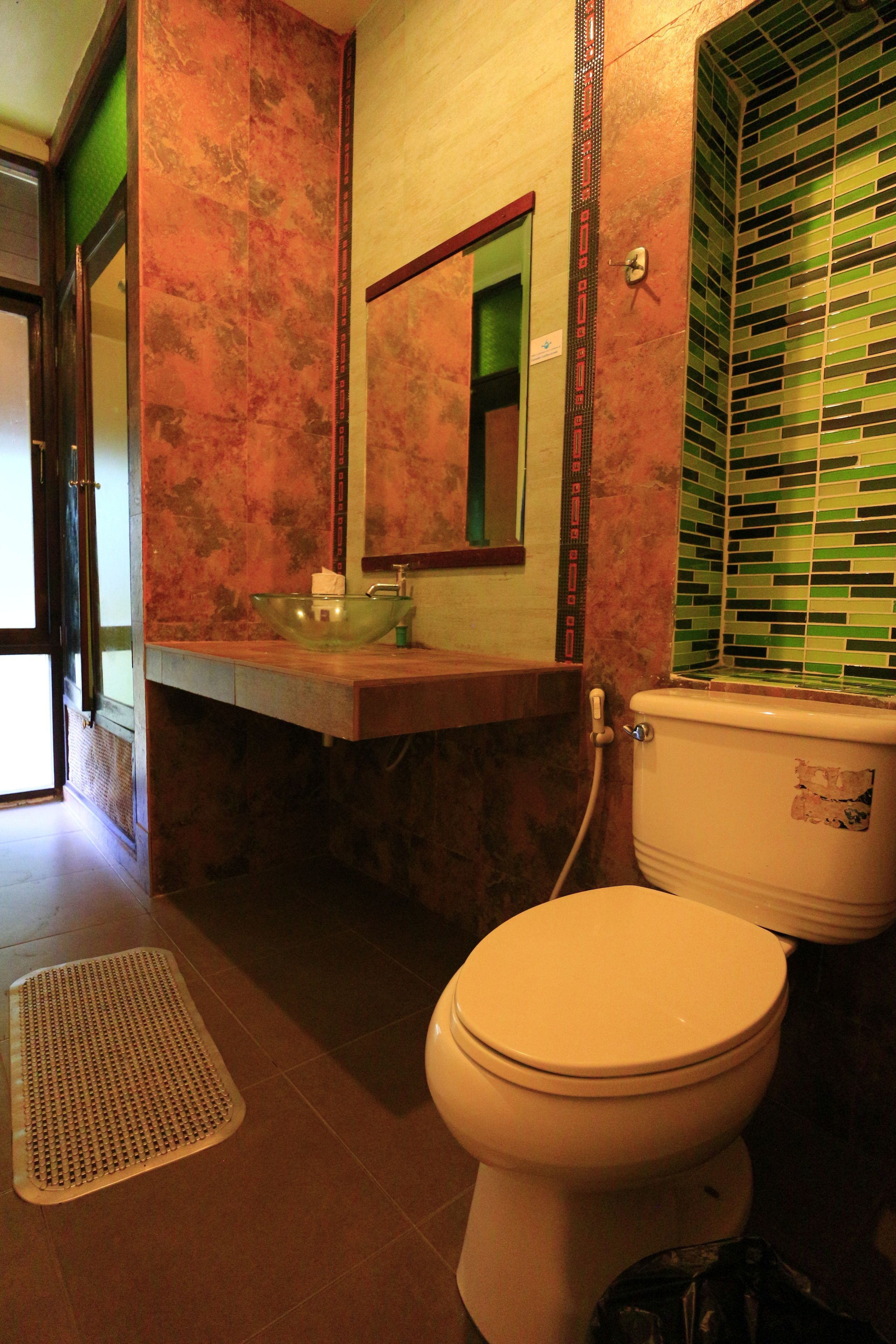 A bathroom with a toilet, sink, and mirror.