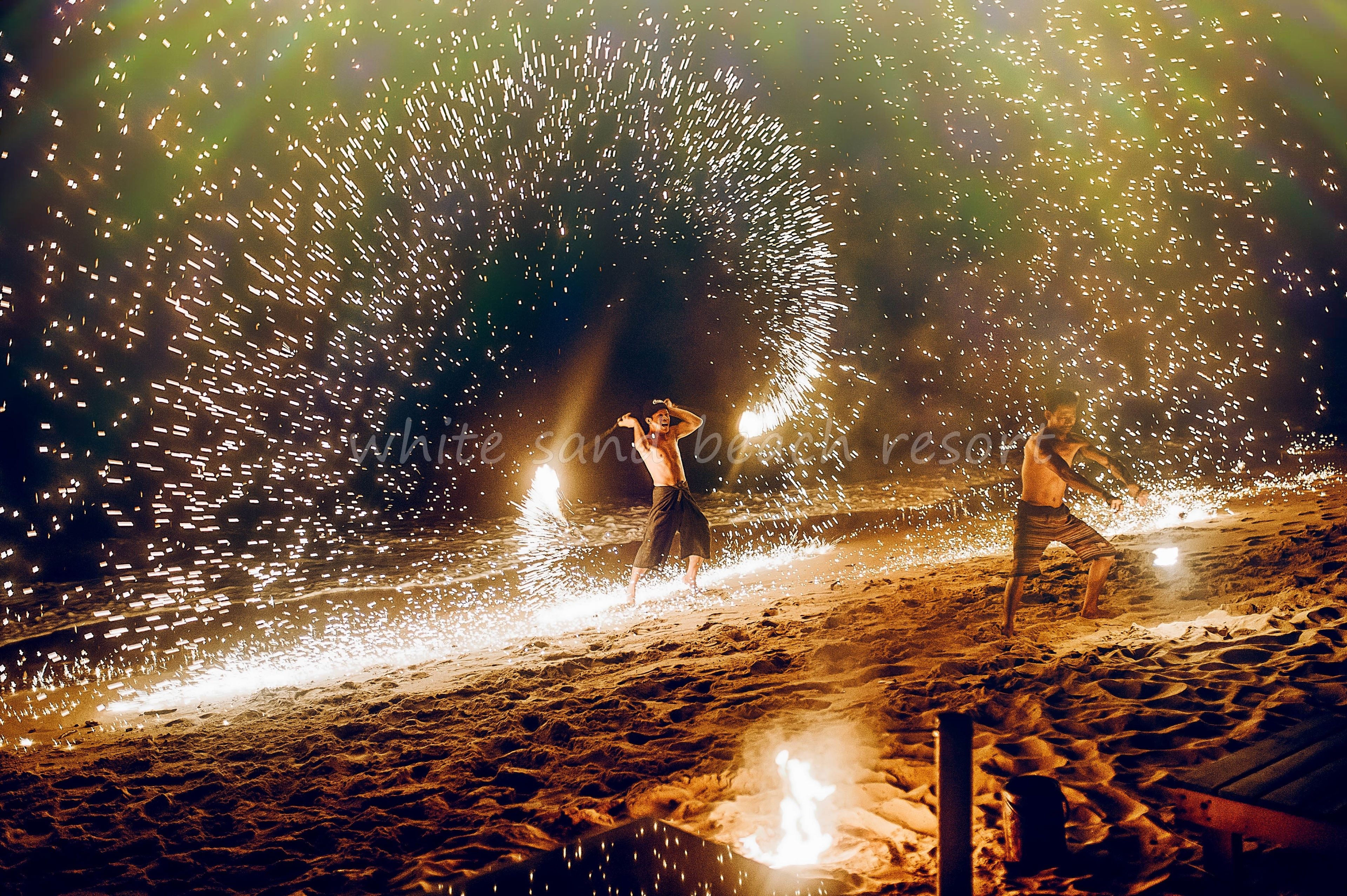 A beach scene with sand and a firework display.