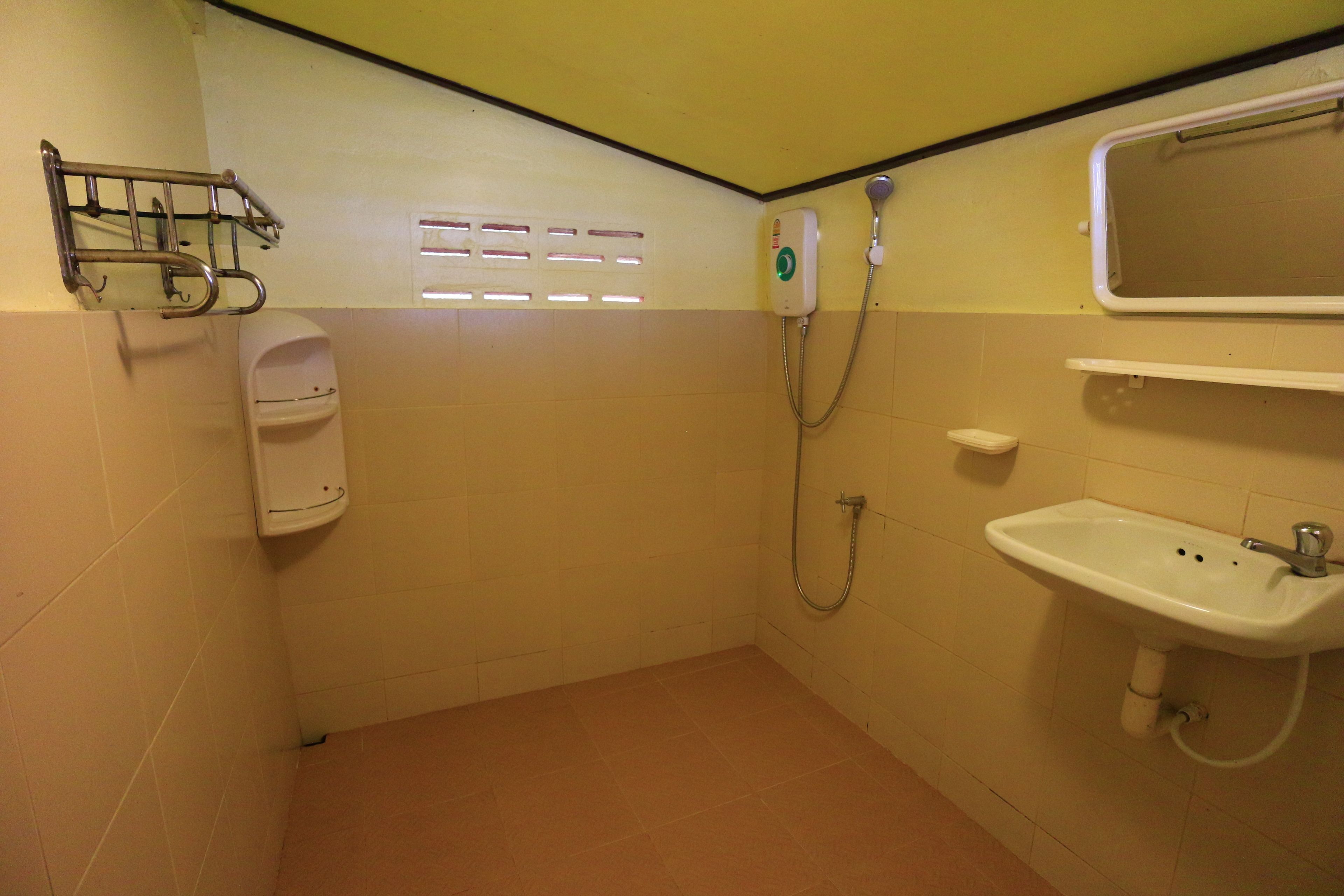 A small bathroom with a toilet, a sink, a shower, and a hand dryer.