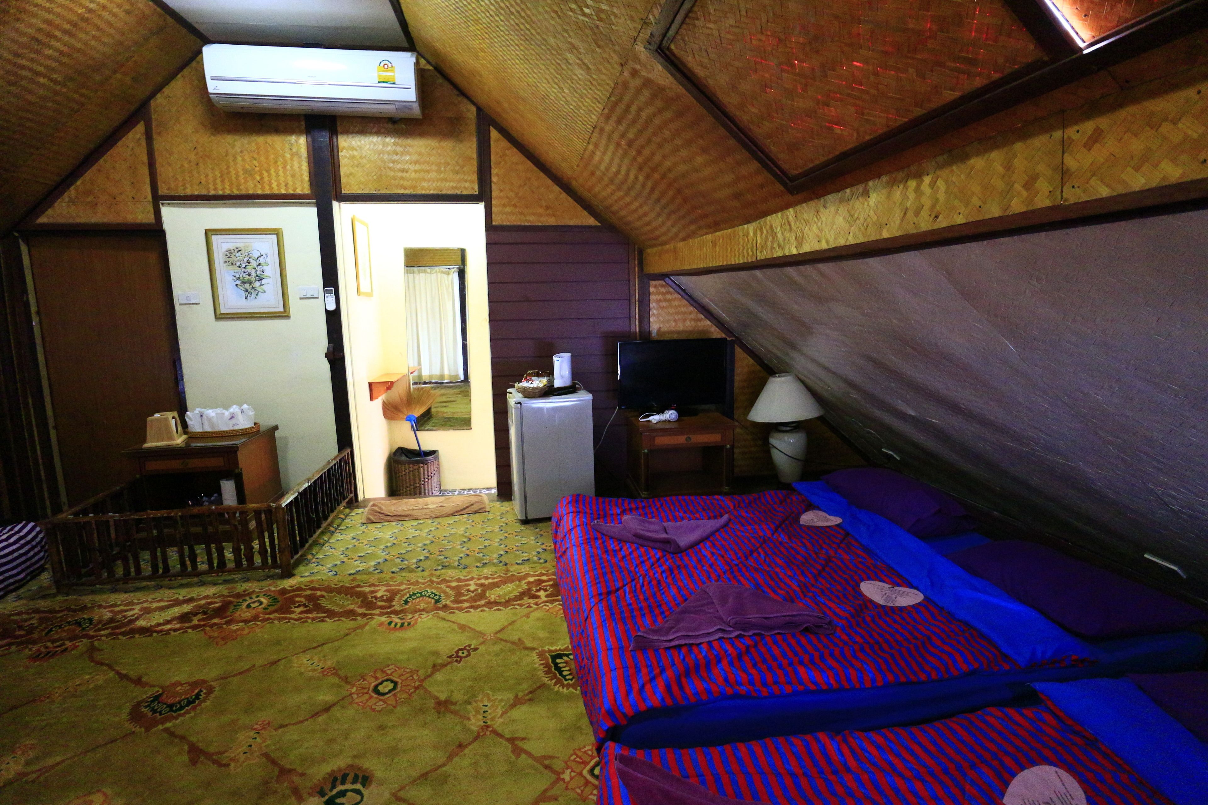 A room with a bed, a television, a small table, and a wall-mounted air conditioner.