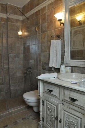 A bathroom with a shower, toilet, vanity, and a mirror.